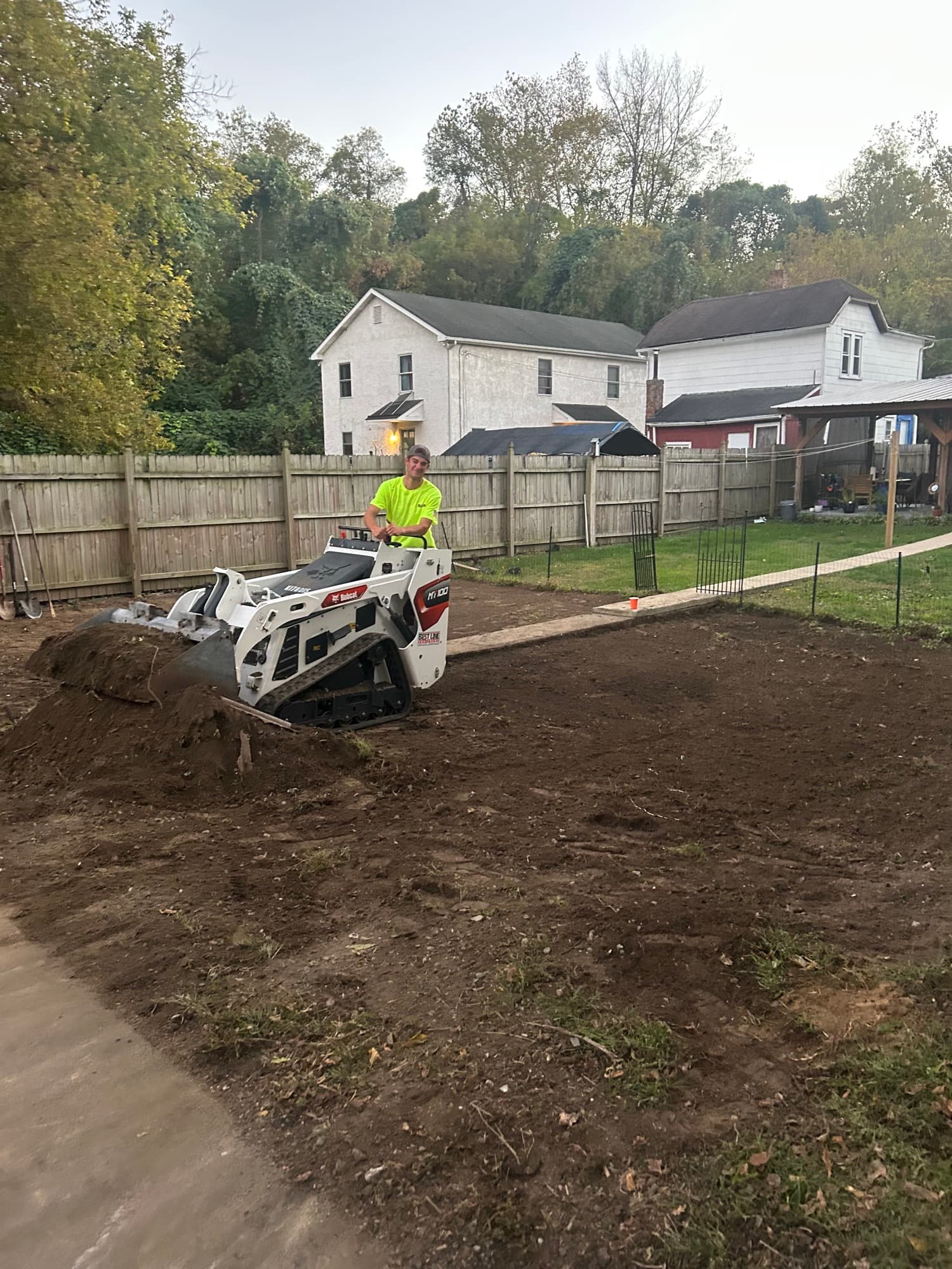 Mini skid steer clearing a backyard lot