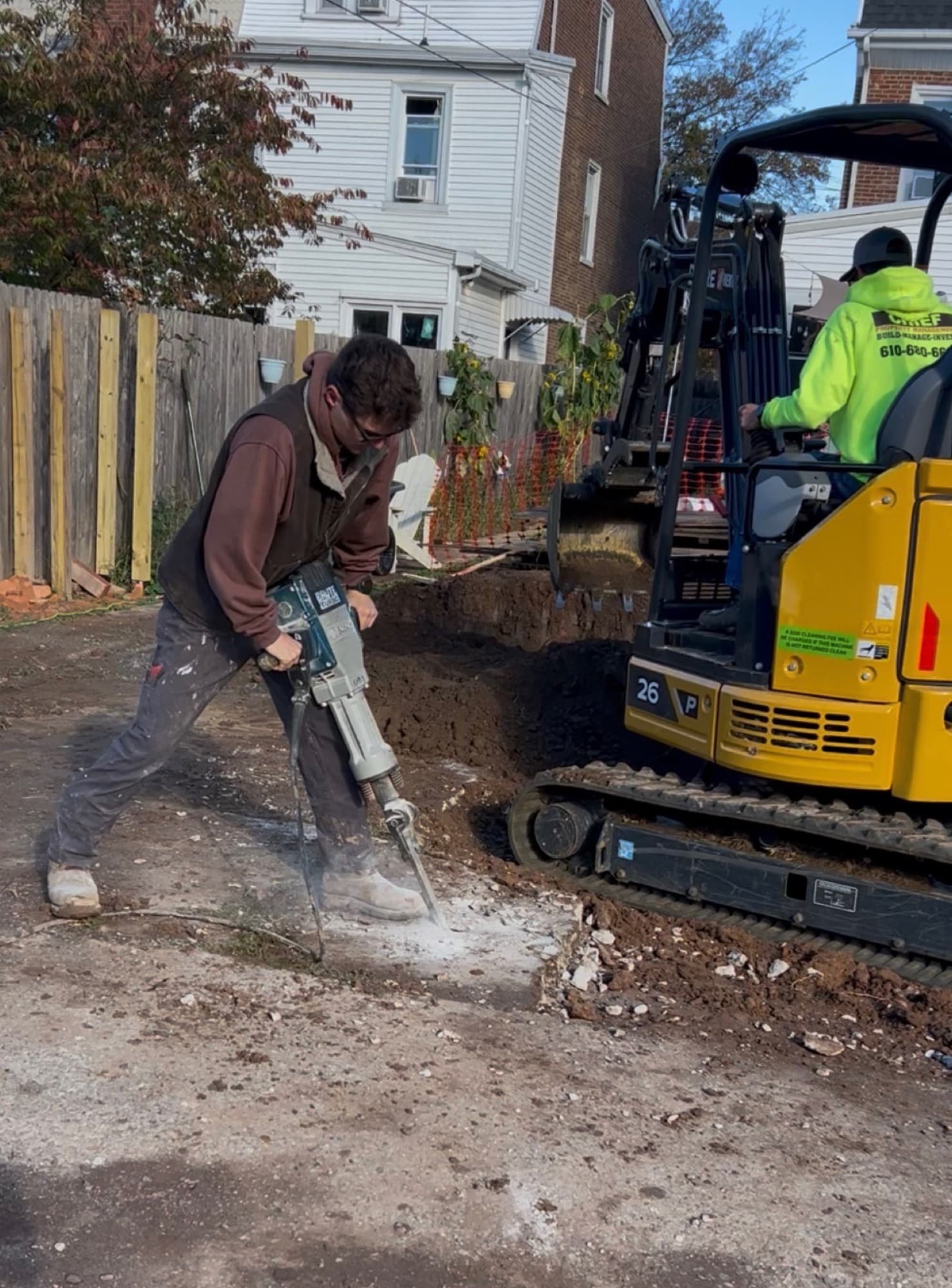 Chief crew jackhammering concrete next to a mini excavator